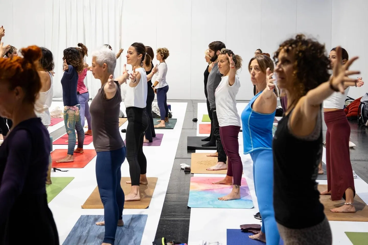 Una classe di yoga di gruppo a Genova in Virabhadrasana II, il guerriero
