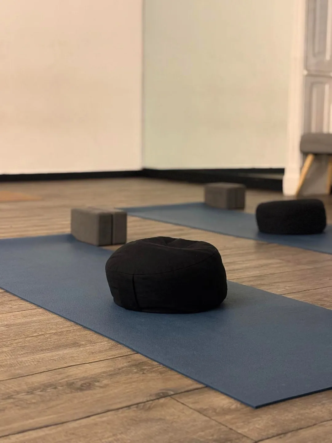 Dettaglio della sala yoga di Genova Carignano: zafu nero su tappetino blu, blocchi di sughero